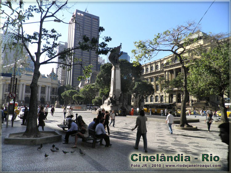 Praça da Cinelândia onde são vistos o Teatro Municipa e a Biblioteca Nacional com muitos pedestres e passantes