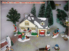 Miniatura de uma casa com garagem, pinheiros e boneco de neve em época de natal