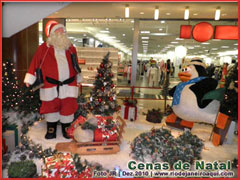 Decoração de natal com papai noel, pinheiros com luzes piscando, neve e presentes